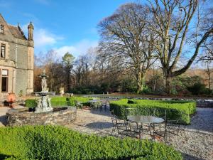 a garden with tables and chairs and a fountain at Penninghame West Lodge in Newton Stewart