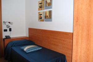 Bett mit blauer Bettwäsche und einem Kopfteil aus Holz in der Unterkunft Telma Hotel in Terracina