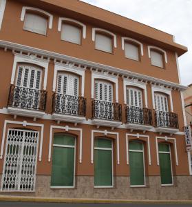 un edificio naranja con puertas verdes y balcones en Hostal Avenida en Tabernas