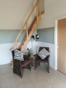 een woonkamer met 2 stoelen en een trap bij ’t Appelke - Hof van Libeek in het heuvelland in Sint Geertruid