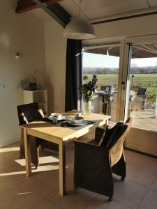 een eettafel en stoelen in een kamer met een raam bij ’t Appelke - Hof van Libeek in het heuvelland in Sint Geertruid