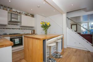 uma cozinha com armários brancos e um balcão com um vaso de flores em Stunning 3 Bedroom House with Garden in Battersea em Londres