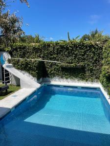 a blue swimming pool next to a hedge at Casa Piscina in Santa Teresa Beach