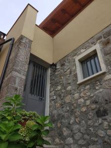 une maison en pierre avec une porte et une fenêtre dans l'établissement PietraViva Casa vacanze FAICCHIO, NON VISANTI, à Visanti