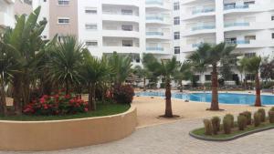 a resort with a pool and palm trees and a building at Good appartement near at the aeroport in Nouaseur