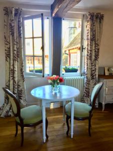 stół z krzesłami i wazon kwiatów na nim w obiekcie La petite duchesse w mieście Vernon