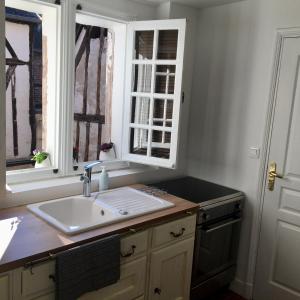 eine Küche mit einem Waschbecken und zwei Fenstern in der Unterkunft La petite duchesse in Vernon
