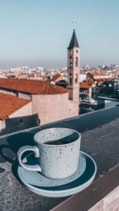 une tasse et une soucoupe sur une corniche avec une tour d'horloge dans l'établissement Mint Hotel, à Prizren