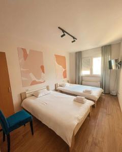 1 dormitorio con 2 camas y silla azul en Mint Hotel, en Prizren