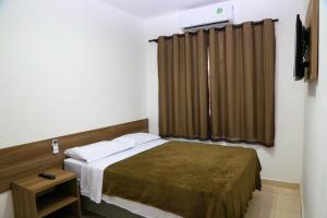 een kleine slaapkamer met een bed en een raam bij Kaluff Hotel in Itaboraí