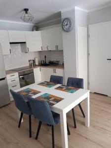 uma cozinha com uma mesa e cadeiras brancas e um relógio em Apartament Monika em Klodzko