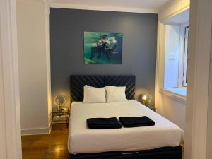 1 dormitorio con 1 cama blanca y una pintura en la pared en Spacious 1 bedroom apartment with a Parking Spot in Chiado, en Lisboa