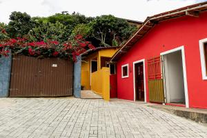 a red building with a fence and flowers on it at Huisje Van Kuringen in Guaramiranga