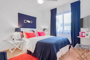 1 dormitorio con 1 cama grande con almohadas azules y rojas en Guayota en Costa Del Silencio