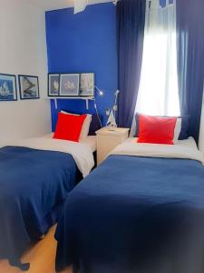 1 dormitorio con 2 camas y almohadas azules y rojas en Guayota en Costa Del Silencio