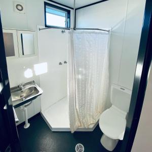 a white bathroom with a toilet and a sink at Magnolia Village Caravan Park in Hervey Bay