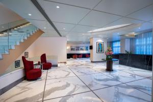 eine Lobby mit roten Stühlen und einer Treppe in der Unterkunft Radisson Blu Marina Hotel Connaught Place in Neu-Delhi