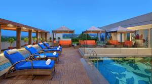 a swimming pool with blue chairs next to a building at Radisson Gwalior in Gwalior