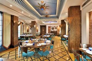 een restaurant met tafels en stoelen en een plafond bij Radisson Noida in Noida