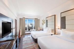 a hotel room with two beds and a flat screen tv at Radisson Jaipur City Center in Jaipur