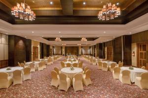 un salón de banquetes con mesas, sillas y lámparas de araña en Radisson Blu Plaza Resort & Convention Centre Karjat en Karjat
