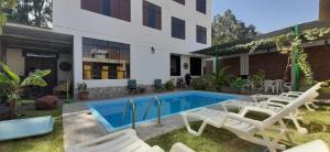 una piscina con sillas blancas y un edificio en Diamond Monkey Lodge en Ica