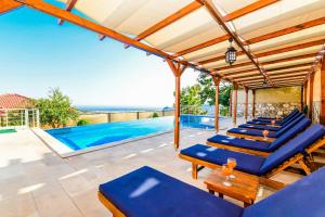 a patio with blue lounge chairs and a swimming pool at Villa Bellevue in Karadere