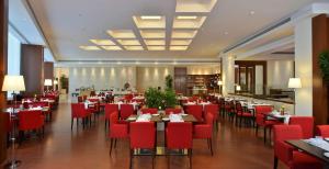 昌迪加爾的住宿－Park Plaza Chandigarh Zirakpur，餐厅内带红色椅子和桌子的用餐室