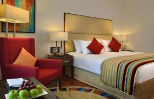 a hotel room with a bed and a red chair at Park Plaza Chandigarh Zirakpur in Chandīgarh