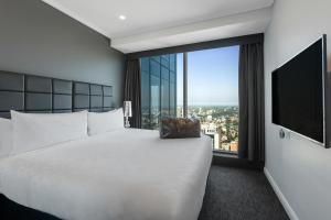 a hotel room with a large bed and a large window at Meriton Suites World Tower, Sydney in Sydney