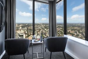 a room with chairs, tables, and windows at Meriton Suites World Tower, Sydney in Sydney