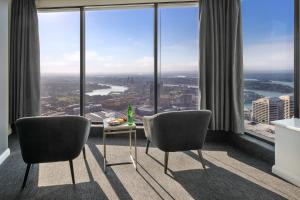 シドニーにあるMeriton Suites World Tower, Sydneyの窓際の椅子2脚とテーブルが備わる客室です。