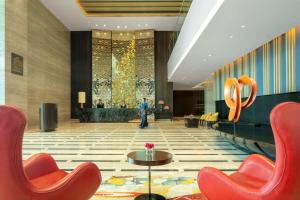 a lobby of a hotel with orange chairs and a table at Radisson Blu Faridabad in Faridabad