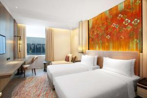 Radisson Lampung Kedaton في بندر لامبونغ: سريرين في غرفة الفندق مع لوحة على الحائط