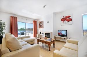 a living room with white furniture and a tv at Casa da Ribeira in Silves