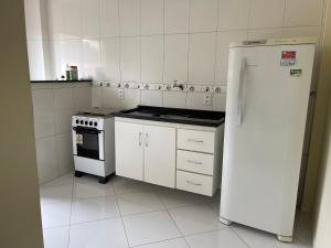 a white kitchen with a refrigerator and a stove at Apartamento encantador em Seabra in Seabra