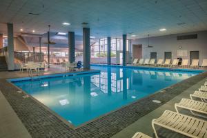 - une grande piscine avec des chaises blanches dans un bâtiment dans l'établissement Best Western Plus Strongsville Cleveland, à Strongsville