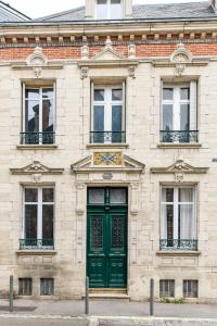 eine grüne Tür in einem Backsteingebäude mit Fenstern in der Unterkunft La Maison de Reina in Troyes