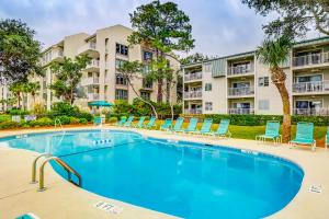 a swimming pool with chairs and a building at Beachwood Place 1H in Hilton Head Island