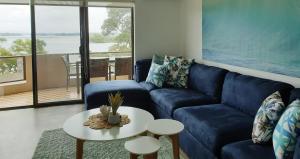a living room with a blue couch and a table at CHILL-OUT LAKESIDE - Wallis Lake Forster in Forster