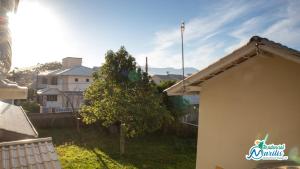 vistas a una casa con un árbol en el patio en Residencial Marilis, en Palhoça