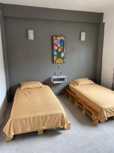 Cette chambre comprend deux lits et un tableau mural. dans l'établissement Lidxi Angela, à Juchitán de Zaragoza