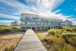 a large house on the beach with a wooden boardwalk at Surf & Sound in Hatteras