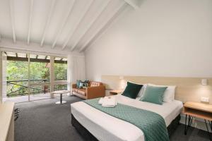 a bedroom with a large bed and a large window at Avoca Beach Hotel in Avoca Beach