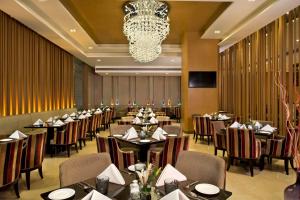 a restaurant with tables and chairs and a chandelier at Radisson Blu Jaipur in Jaipur