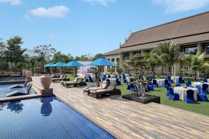 卡尔贾特Radisson Blu Plaza Resort & Convention Centre Karjat的一个带游泳池、桌椅的度假酒店
