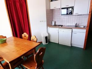 a kitchen with a table and chairs and a kitchen with white cabinets at Appartement Saint-François-Longchamp, 2 pièces, 6 personnes - FR-1-635-1 in Saint-François-Longchamp