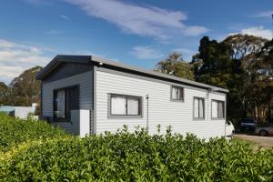 a small white house with a black roof at Woodmans Hill Motel in Ballarat