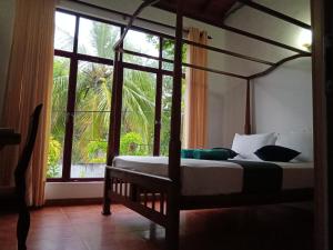 a bedroom with a canopy bed and a large window at Kolition Villa in Dickwella