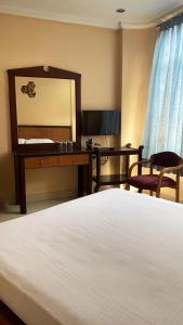 a bedroom with a bed and a desk and a mirror at Hotel Meridian Palace in Kannur